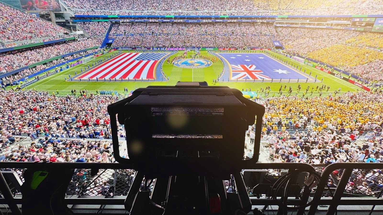 Broadcast camera on a high gantry overlooking a packed stadium during the pre-match ceremony